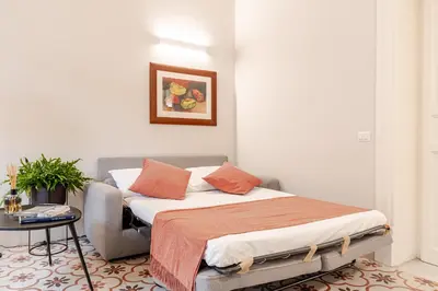 a bedroom with a bed with orange pillows and a table at Zahir Suite Apartment in Palermo
