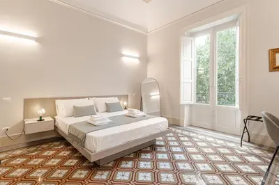 a white bedroom with a large bed and a window at Zahir Suite Apartment in Palermo
