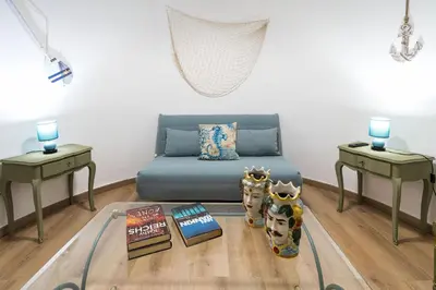 a living room with a blue couch and two tables at Casa Trionfante in Santa Flavia