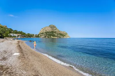 a woman walking on a beach near the water at Terrazza Trionfante in Santa Flavia