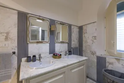 a bathroom with two sinks and two mirrors at Terrazza Trionfante in Santa Flavia