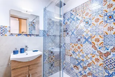 a bathroom with a sink and a shower with blue and white tiles at Cappuccini 62 House in Palermo