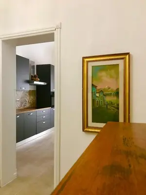 a kitchen with a painting on the wall and a wooden table at Palermo Maison in Palermo