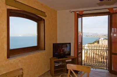 a room with a view of the ocean and a television at Balconi Sul Mare Appartamenti in Castellammare del Golfo