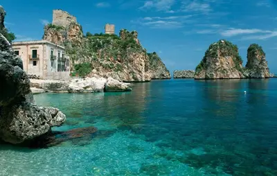 a view of a body of water with rocks and a building at Balconi Sul Mare Appartamenti in Castellammare del Golfo