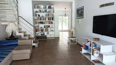 a living room with a staircase with a tv and bookshelves at Villa Ginevra in Mondello
