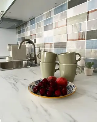 a plate of fruit on a counter with two cups at Zahira Apartment in San Vito lo Capo