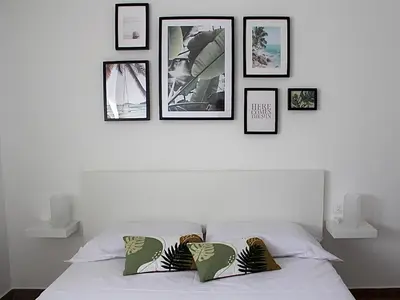 a white bed with four pictures on the wall at Zahira Apartment in San Vito lo Capo