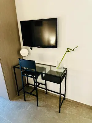 a desk with a chair and a tv on a wall at L'Oasi del Tirreno in Lascari