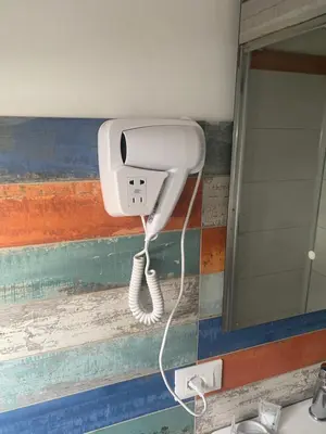 a blow dryer on a bathroom wall next to a mirror at L'Oasi del Tirreno in Lascari