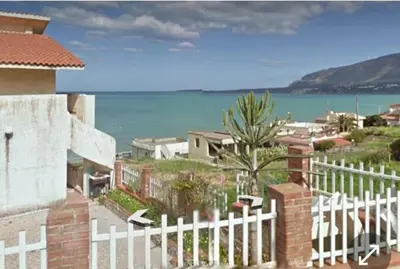 a white fence in front of a house with the ocean at Sizilien 3 in Trappeto
