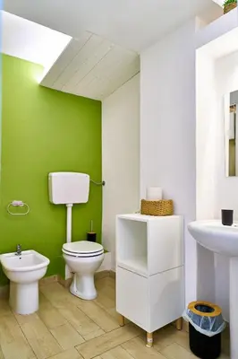 a green bathroom with a toilet and a sink at Cara Palermo in Palermo
