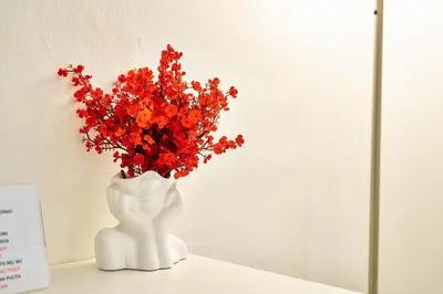 a white vase with red flowers in it at Cara Palermo in Palermo