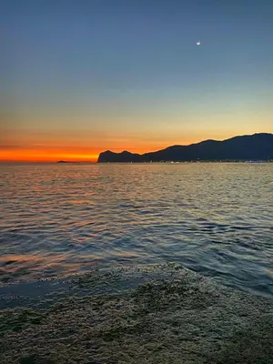 a sunset over the water with mountains in the background at Domus Mea Apartments in Carini