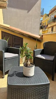 a patio with wicker chairs and a table with a potted plant at Domus Mea Apartments in Carini