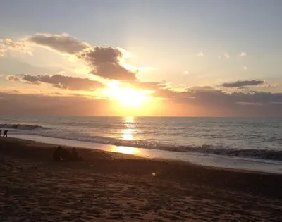 a sunset on the beach with people and the ocean at Anna holidays in Lascari