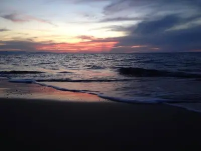 a sunset on the beach with the ocean at Anna holidays in Lascari
