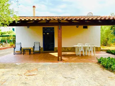 a patio with chairs and a table and a house at Villetta Verde Mare - Scopello in Scopello