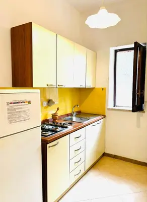 a kitchen with white cabinets and a sink and a refrigerator at Villetta Verde Mare - Scopello in Scopello