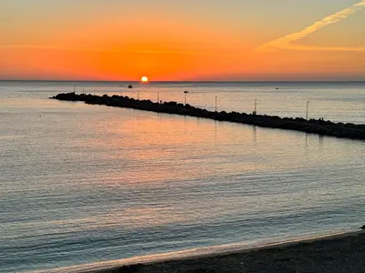a beach with the sun setting over the ocean at Sicilia biedda casa vacanze in Terrasini