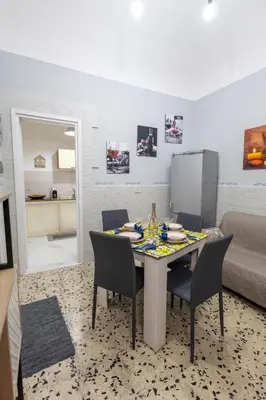 a dining room with a table with chairs and a couch at Gioiello di casa in Palermo