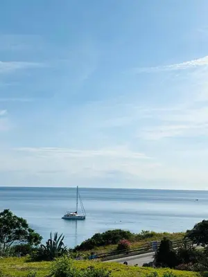 a sailboat in the ocean with a ship in the water at Terrazza Vitaloca in Scopello