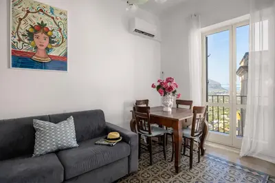 a living room with a couch and a table with chairs at La Castellana Apartments, vista panoramica sul mare, nel cuore storico di Carini, a due passi dal Duomo e dal castello in Carini