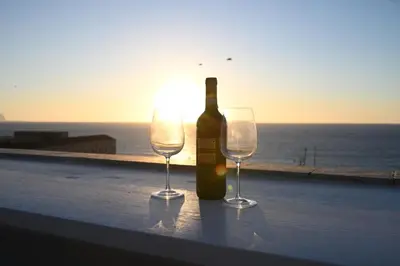 a bottle of wine and two wine glasses on a ledge at Riad Casa Vacanze in Terrasini