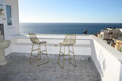 two chairs sitting at a bar on a balcony with the ocean at Riad Casa Vacanze in Terrasini