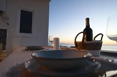 a table with two plates and a bottle of wine at Riad Casa Vacanze in Terrasini