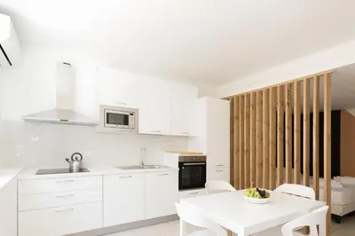 a white kitchen with a white table and chairs at Visitsicilia Vasile 9 in Castellammare del Golfo