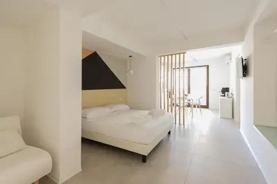 a white bedroom with a bed and a chair at Visitsicilia Vasile 9 in Castellammare del Golfo
