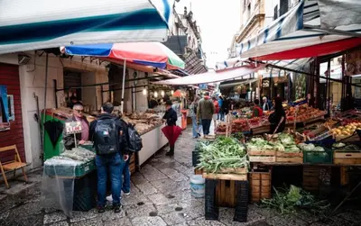 a group of people walking through an outdoor market at Ginevra House in Palermo