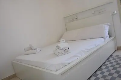 a white bed with white sheets and towels on it at apartment by the sea Mondello beach in Palermo