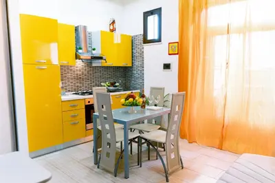 a kitchen with yellow cabinets and a table and chairs at Appartamenti Bellini in Castellammare del Golfo