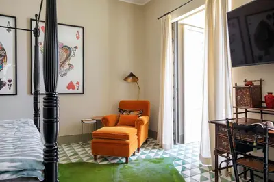 a bedroom with an orange chair and a bed at Trinacria Luxury Suite in Palermo