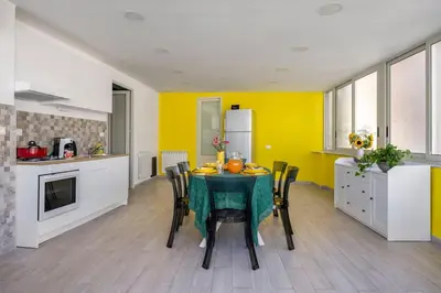 a kitchen with a table with chairs and yellow walls at Vista San Domenico in Palermo