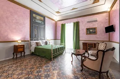 a bedroom with pink walls and a bed and a table at GuestHost - La Dimora dei Mille - Roomy Apartment with Terrace in Palermo