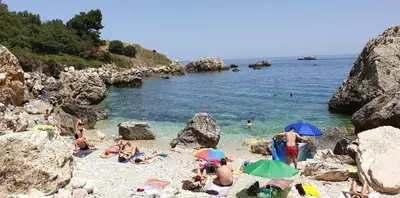 a group of people sitting on a beach with umbrellas at Casa delle Stelle in Scopello