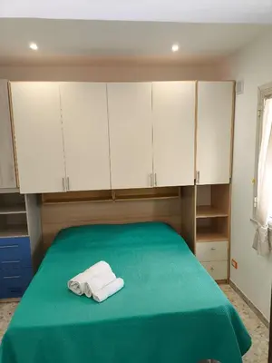 a bedroom with white cabinets and two towels on a bed at Home For You in Carini