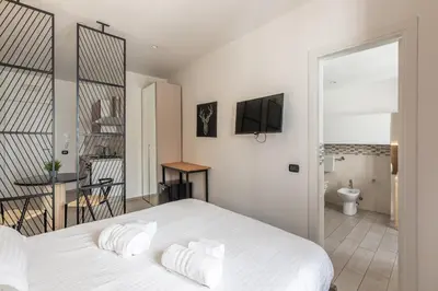 a bedroom with a white bed and a bathroom at Naos Home - Alle Spalle del Teatro Massimo in Palermo