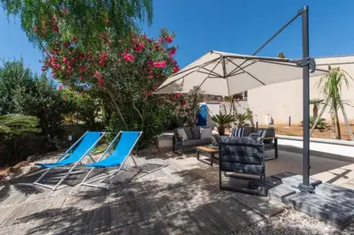 a group of chairs and an umbrella on a patio at Villa Makar Seaview in Macari