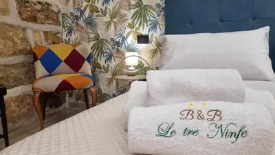 a hotel room with a bed and a chair and towels at LE TRE NINFE Cinisi in Cinisi