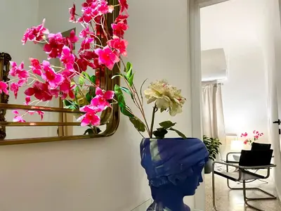 a blue vase with pink flowers in front of a mirror at City SEA DOWNTOWN in Palermo