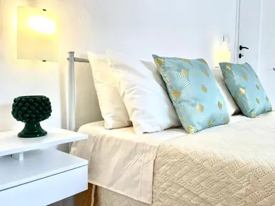 a white bed with pillows on it next to a table at City SEA DOWNTOWN in Palermo