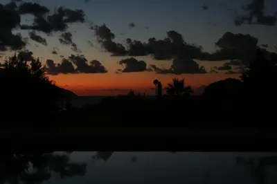 a sunset with a water tower in the distance at villa grecale in Castellammare del Golfo