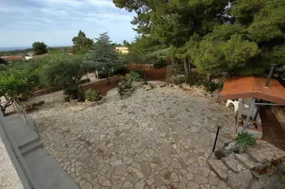 a stone patio with trees and shrubs at villa grecale in Castellammare del Golfo