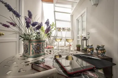 a table with two glasses of wine and a vase with flowers at Pane Amore e Marmellata in Palermo
