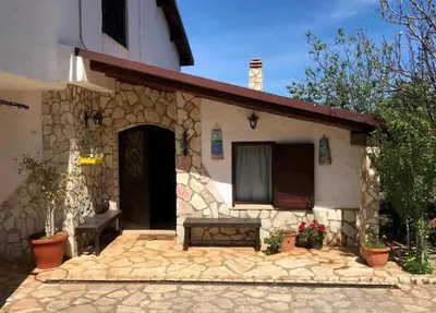 a stone house with a bench in front of it at La villa di Turi in Castellammare del Golfo