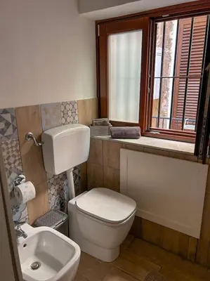 a bathroom with a toilet and a sink and a window at Ai Pupi Siciliani in Palermo